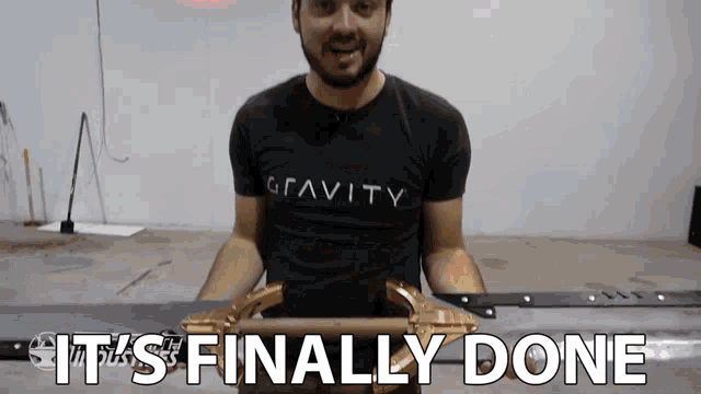 a man wearing a shirt that says gravity is holding a sword and says it 's finally done