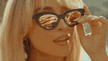 a woman wearing a pair of sunglasses with a reflection of a man in them