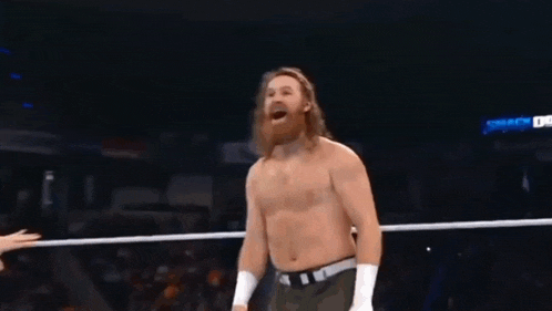 a man with a beard is standing in a wrestling ring with his mouth open .