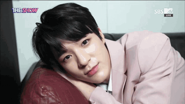 a young man in a pink suit is laying on a couch with the show sbs live written on the bottom