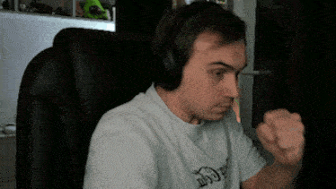 a man wearing headphones is sitting in a chair with his fist raised