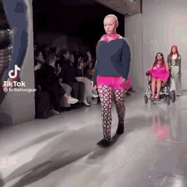 a woman in a wheelchair walks down the runway at a fashion show sponsored by tiktok