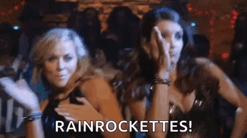 two women are dancing together in a club and one of them is holding her hand to her chest .