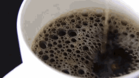 a close up of a cup of coffee with bubbles in it .
