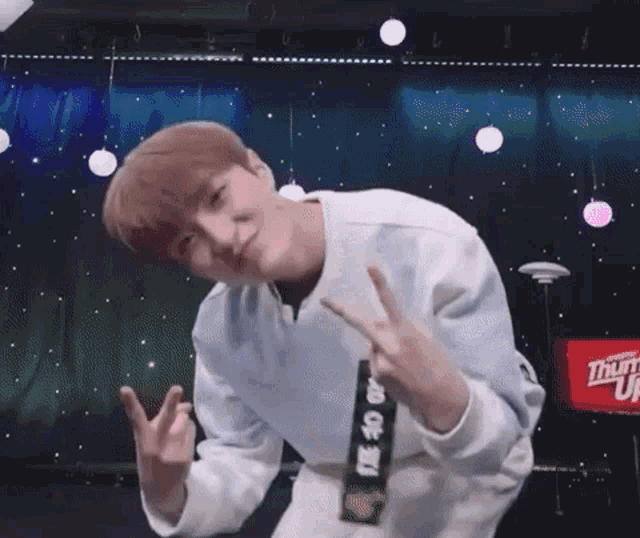 a young man is making a peace sign with his hands in front of a stage .