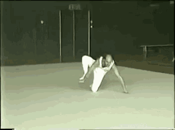 a man is crawling on the floor in a gym with a sign that says exit