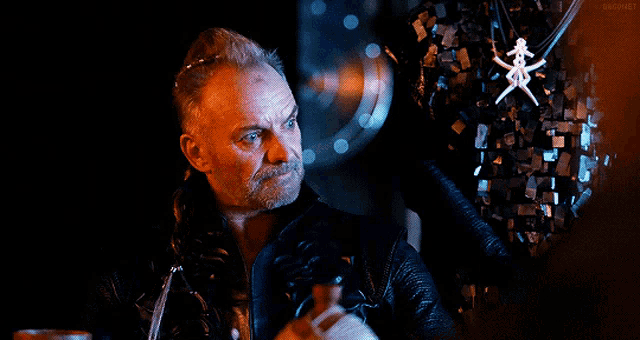 a man with a beard is holding a gun in front of a skeleton necklace