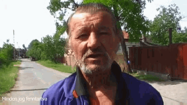 a man with a beard wearing a blue jacket is standing on a street talking