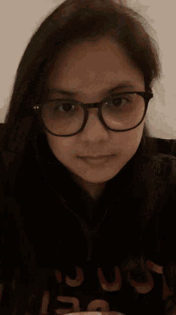 a woman wearing glasses and a black turtleneck is blowing a kiss