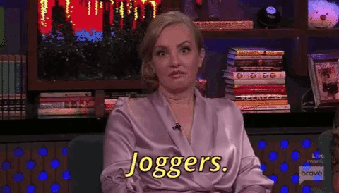 a woman in a satin robe is sitting in front of a bookshelf and says joggers .