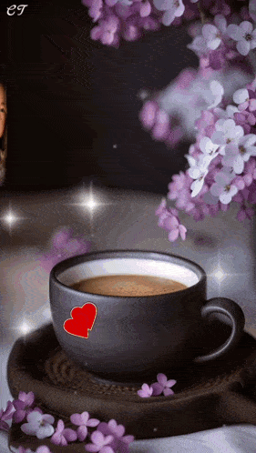 a cup of coffee with two red hearts on it and purple flowers in the background