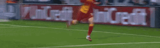 a soccer player is running on a field in front of a banner that says unicredit