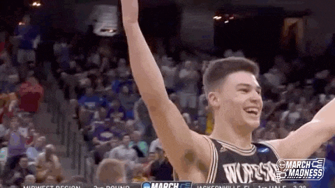 a man in a basketball uniform is raising his arms in the air .