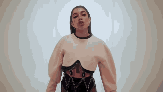 a woman with a tattoo on her chest is wearing a white top and black bottoms