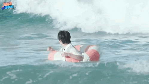 a man in a life preserver is floating in the ocean .