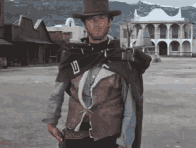 a man wearing a cowboy hat and a cape has the letter d on his vest