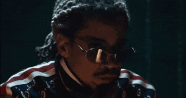 a man wearing sunglasses and a gucci shirt is looking down .