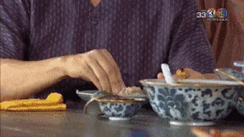 a person is sitting at a table with bowls of food and a yellow napkin .