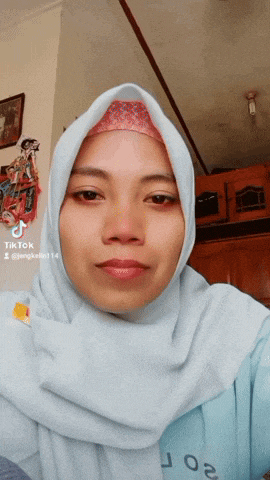 a woman wearing a hijab and a blue shirt has a tiktok account