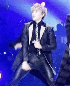 a man in a suit and tie is dancing on a stage while holding a microphone .