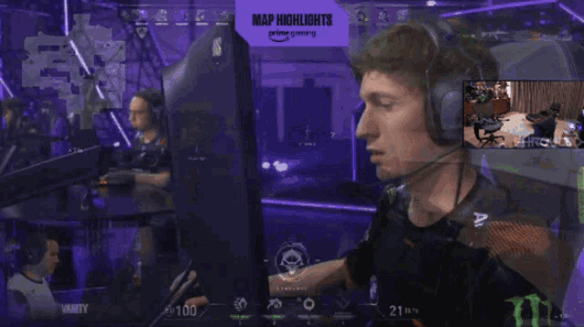 a man wearing headphones is sitting in front of a monitor with a sign that says map highlights on it