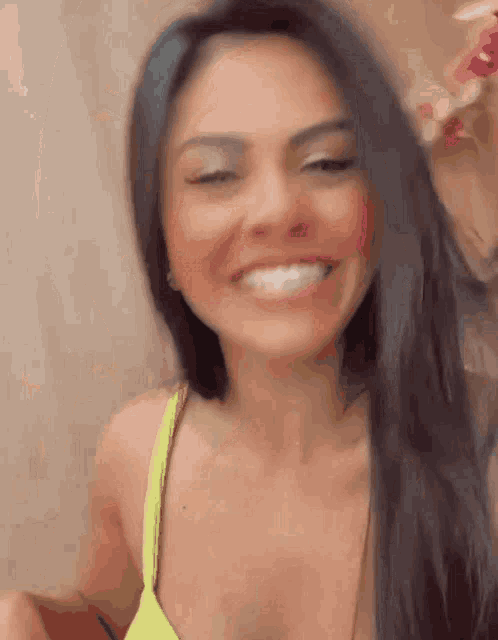 a woman in a yellow bikini top is smiling and holding her hair .