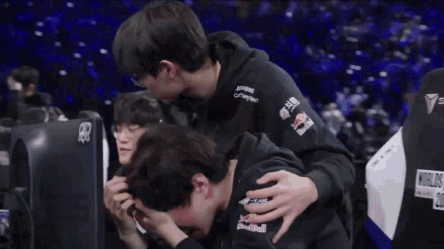 a man wearing a red bull sweatshirt holds another man 's head