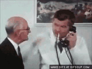 a man in a suit and tie is talking on a telephone with another man .