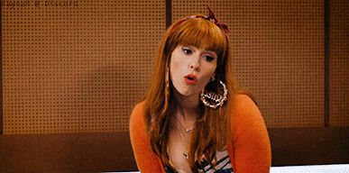 a woman with red hair wearing hoop earrings and a headband