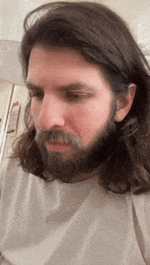 a man with long hair and a beard is looking down