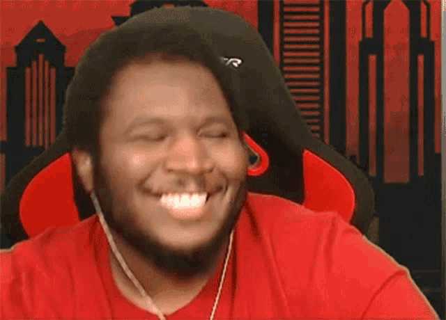 a man in a red shirt is smiling while wearing headphones