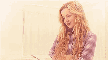 a blonde woman in a purple plaid shirt is sitting in a hospital bed