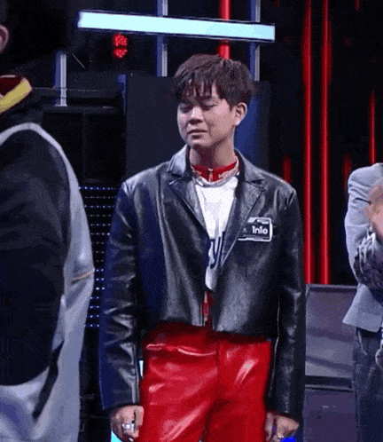 a man wearing a black leather jacket and red pants has a name tag that says into