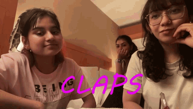 three girls are sitting on a bed with the word claps written on the bottom