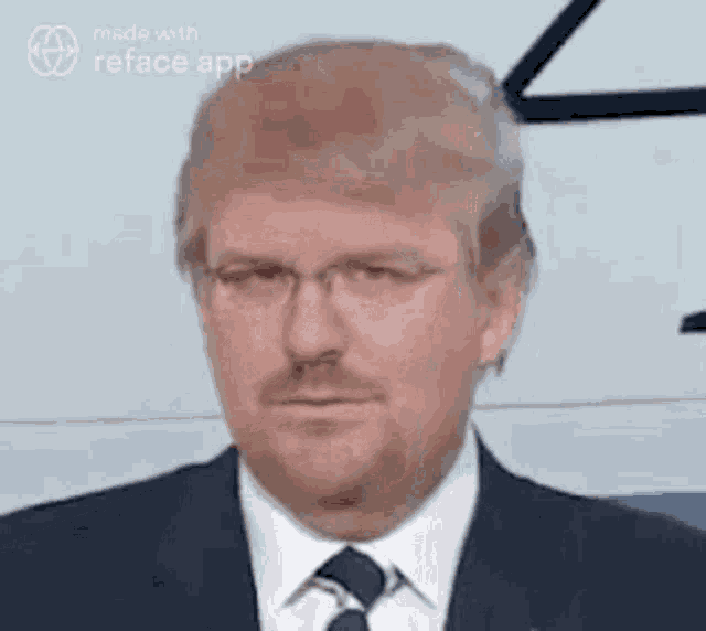 a man in a suit and tie with glasses and a beard is making a funny face .