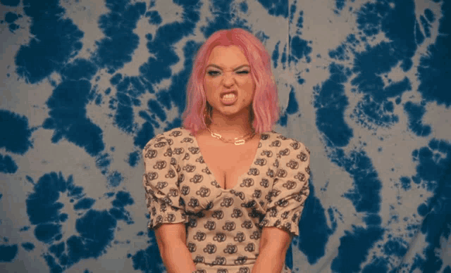 a woman with pink hair is making a funny face in front of a blue and white background