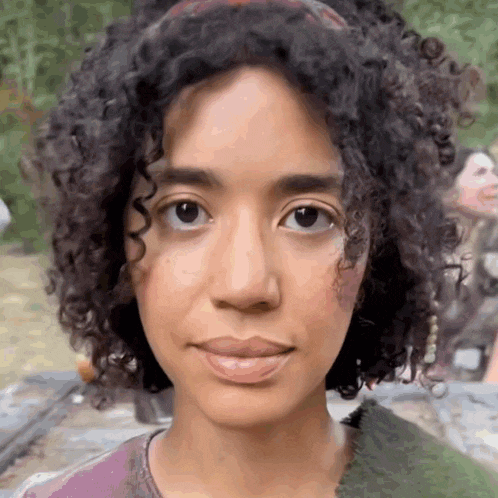 a close up of a woman 's face with curly hair and a headband
