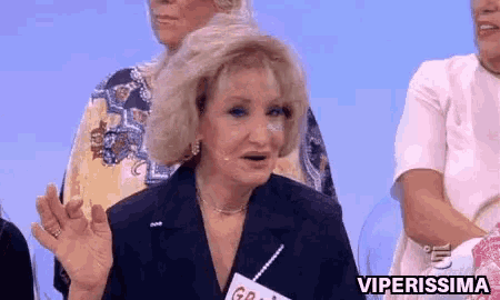 a woman with a name tag that says viperissima stands in front of a group of people .
