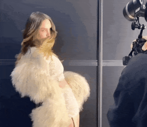 a woman wearing a white fur coat is being photographed
