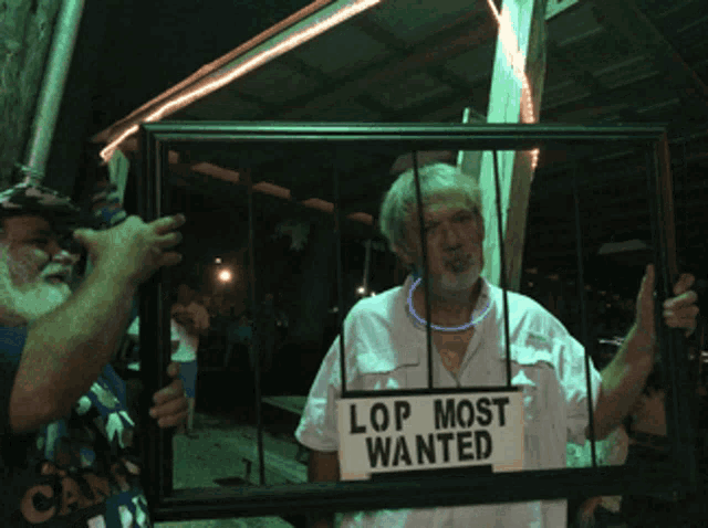 a man is holding a picture frame that says lop most wanted