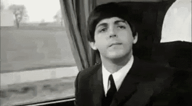 a black and white photo of a man in a suit and tie sitting in a train car .