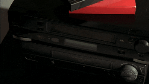 a hand pointing at a vhs player that is on
