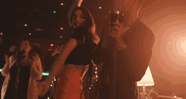 a man is singing into a microphone while a woman dances in the background
