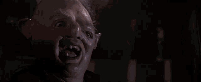 a close up of a man with a mask on his face making a funny face in a dark room .