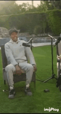 a man is sitting in a chair in front of a microphone on a grassy field .