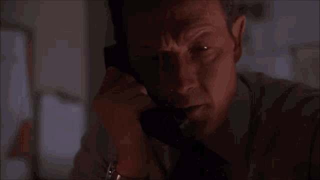 a man in a suit and tie is talking on a cell phone in the dark .