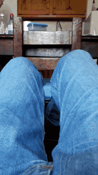 a person wearing blue jeans sits on a wooden table