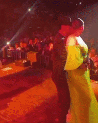 a woman in a green dress is dancing with a man in a red shirt that says ' rj ' on it