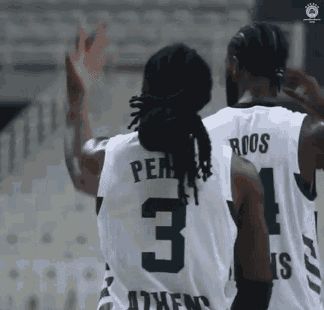 a couple of basketball players are standing next to each other and one of them has the number 3 on his back .