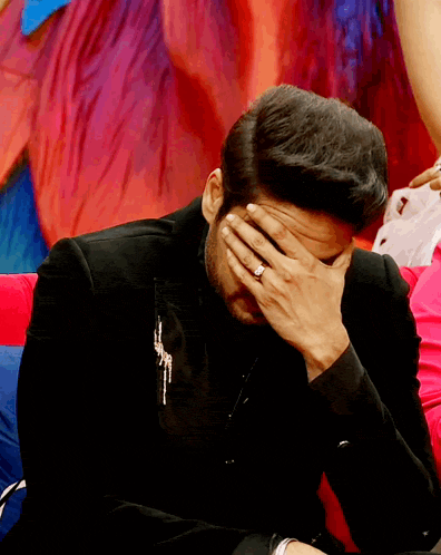 a man with a ring on his finger covers his face with his hand